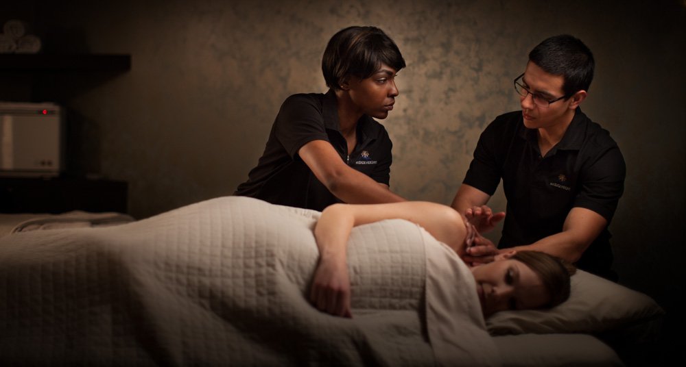 Two massage therapists learning about massage techniques
