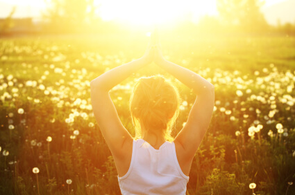 Woman in fields at golden hour meditating