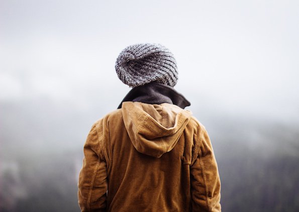 Person in hooded jacket and beanie looking at mountains